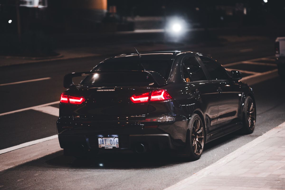 Black sports car with spoiler captured under streetlights
