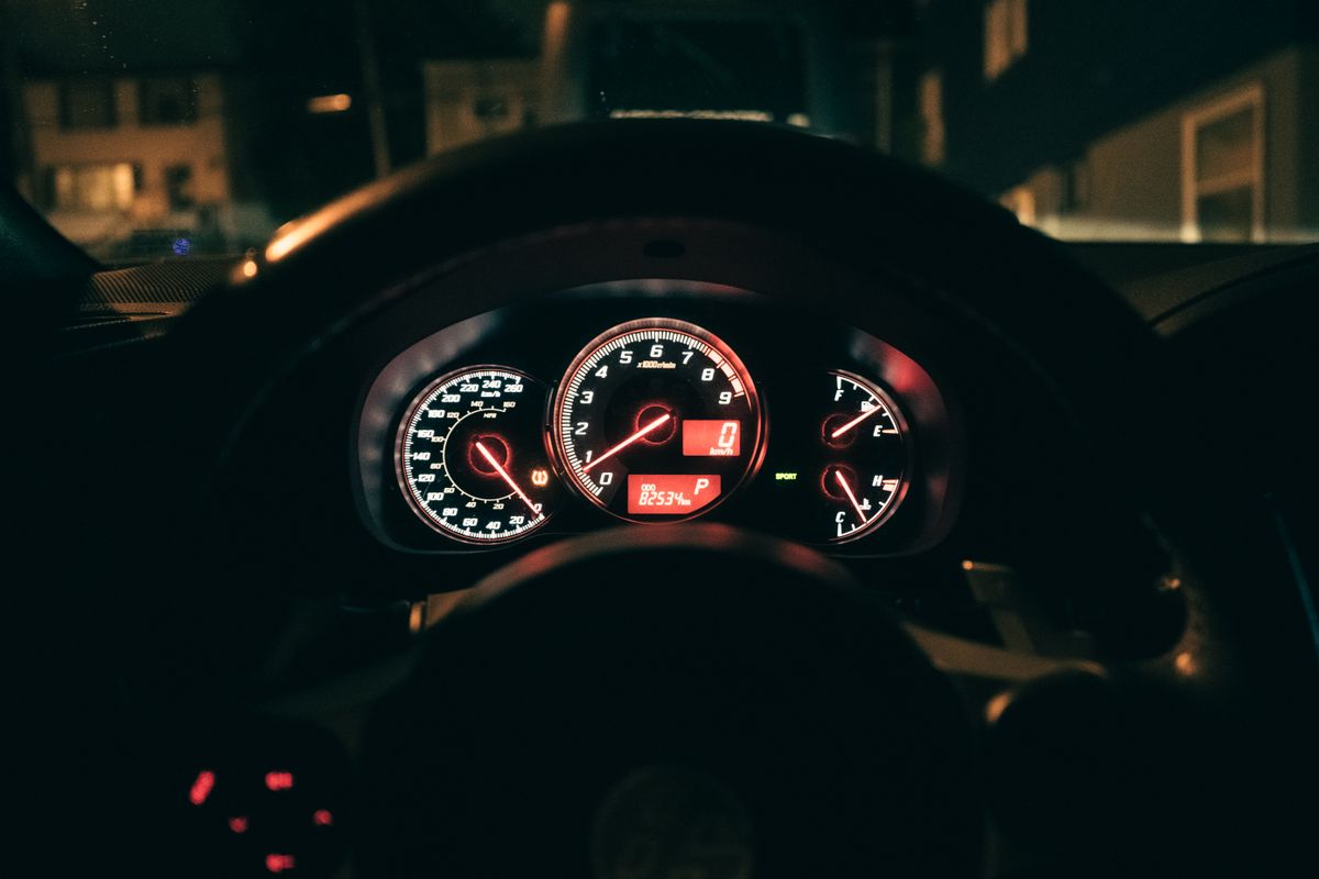 Close-up of a dimly lit car dashboard showing an illuminated speedometer at night