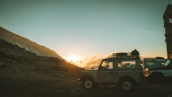 A rugged vehicle parked in a mountainous region at sunset
