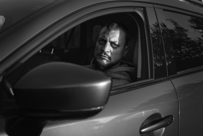 Serious bearded man looking out from a vehicle in a monochrome setting
