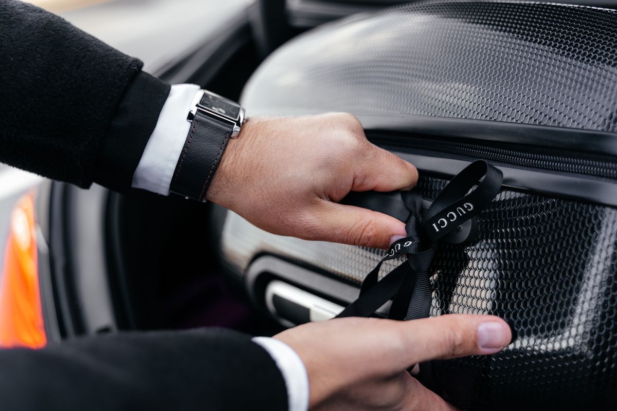 Close-up of hands unpacking an elegant suitcase from a car trunk