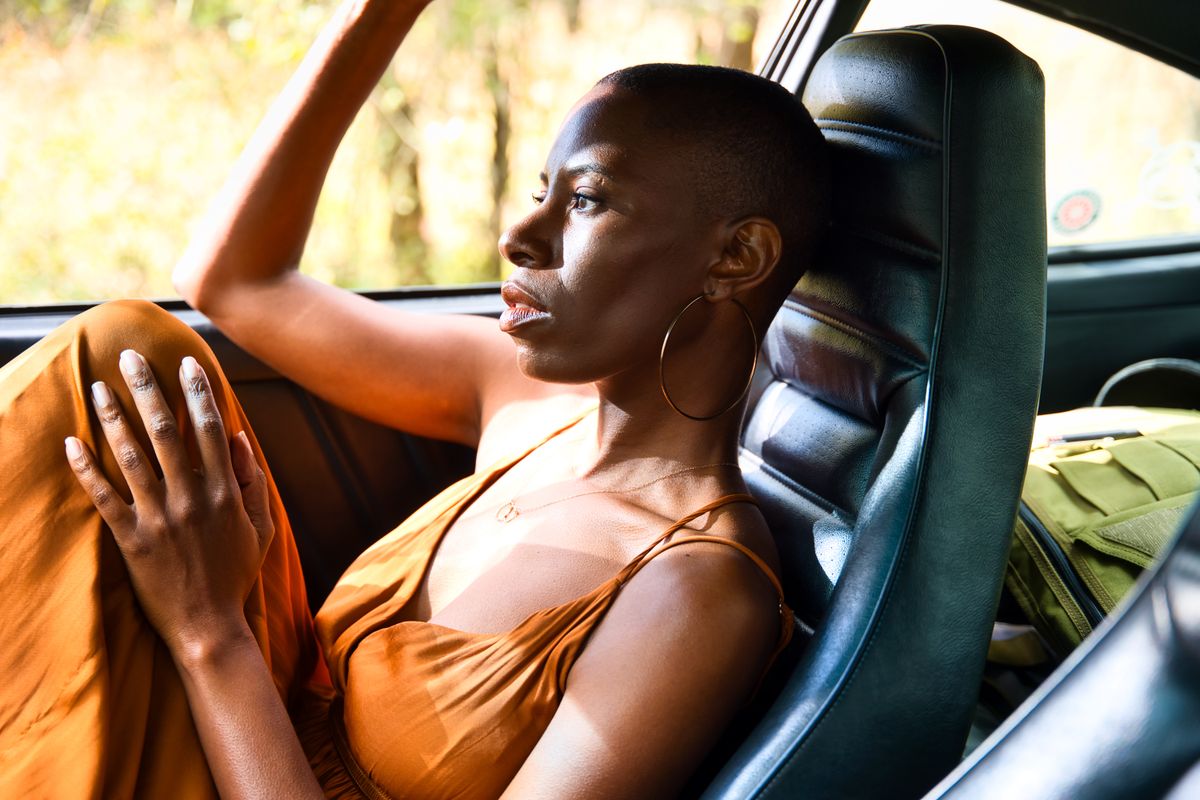 A woman in a car gazes contemplatively out the window with sunlight