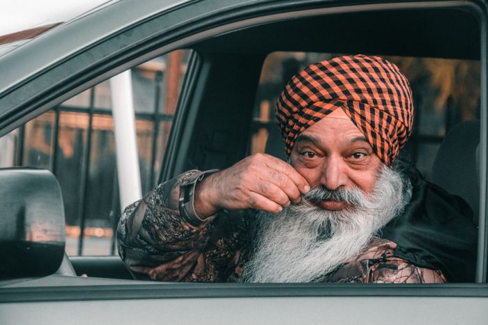 Elderly man with turban smiling in car