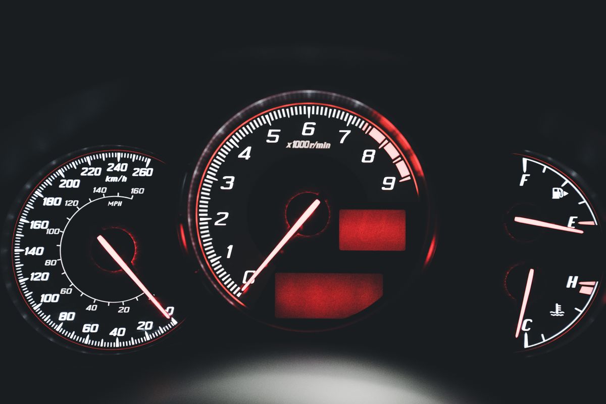 Close-up of an illuminated modern car dashboard with speedometer and gauges