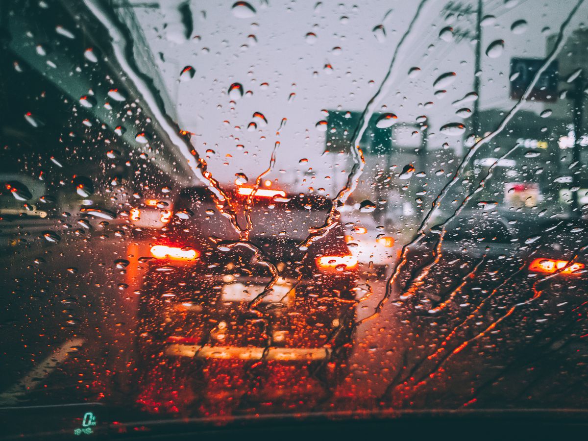 Blurred city traffic seen through a rain-soaked windshield