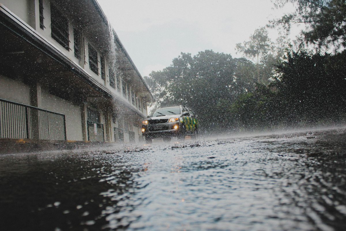 A car navigates a flooded street amid heavy rain and stormy weather