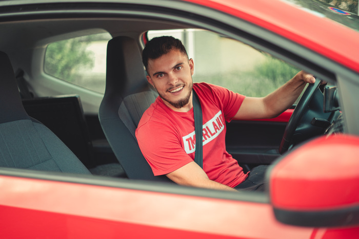 Smiling man sitting in red car