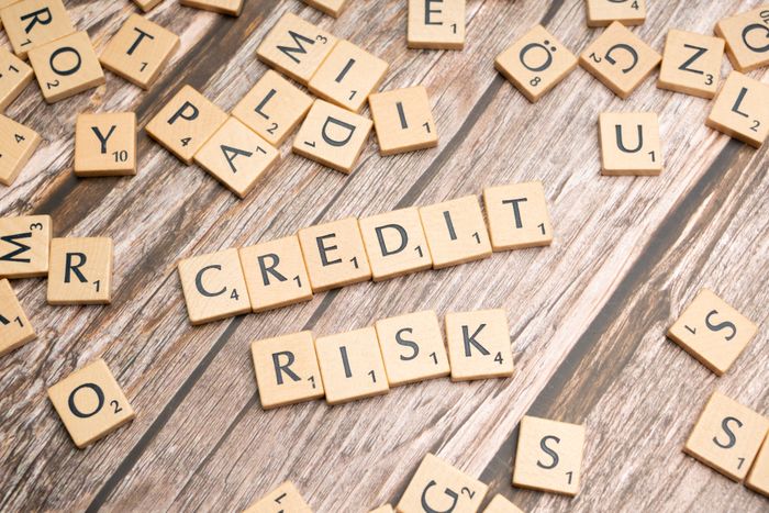Scattered wooden letter tiles spelling 'credit risk' on a rustic wooden surface