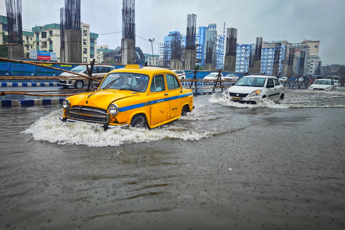 A yellow taxi battles flooding on urban streets in Kolkata, India