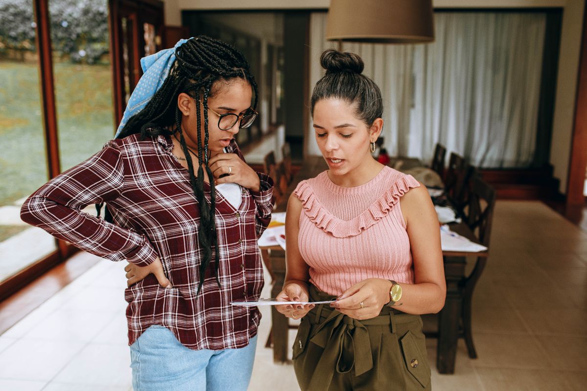Two women engage in a discussion while examining a document in a well-lit room