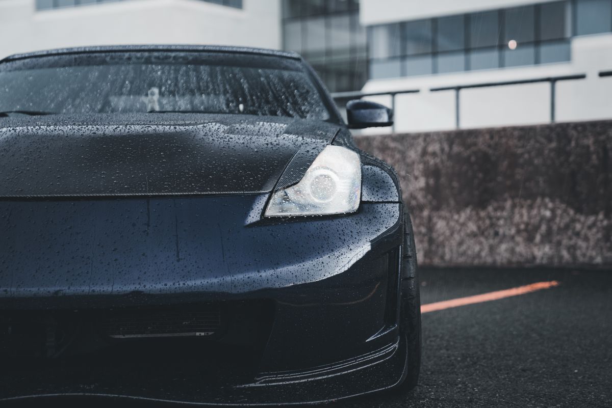 Closeup shot of a sleek black car with rain droplets on the hood