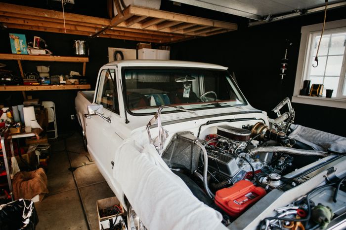 A vintage pickup truck undergoing engine repairs in a well-equipped home garage