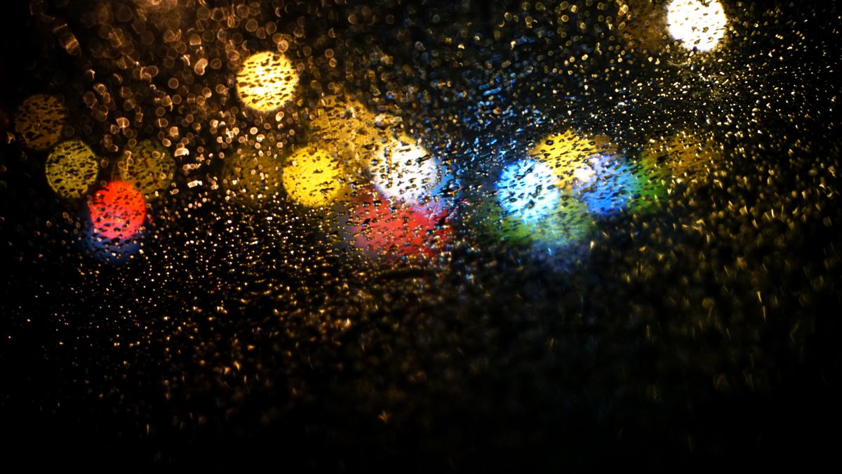 Abstract image of colorful raindrops on glass with bokeh lights at night