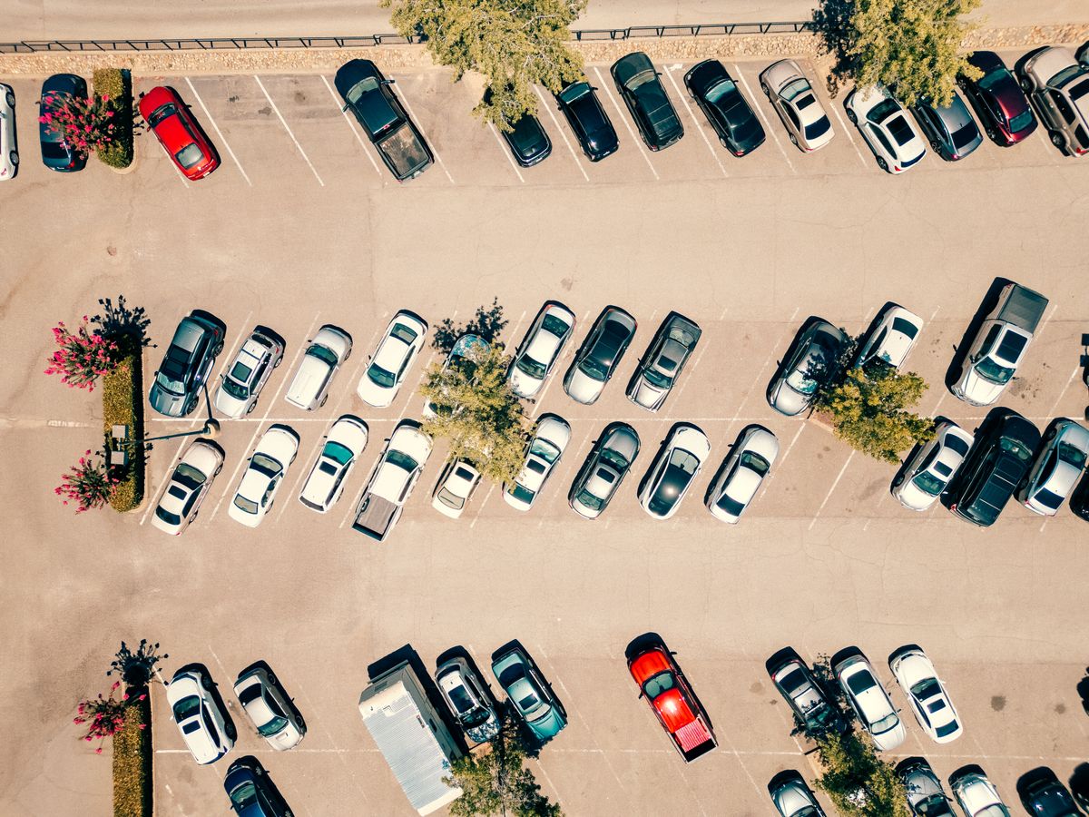 Aerial shot of a parking lot filled with cars on a bright, sunny day