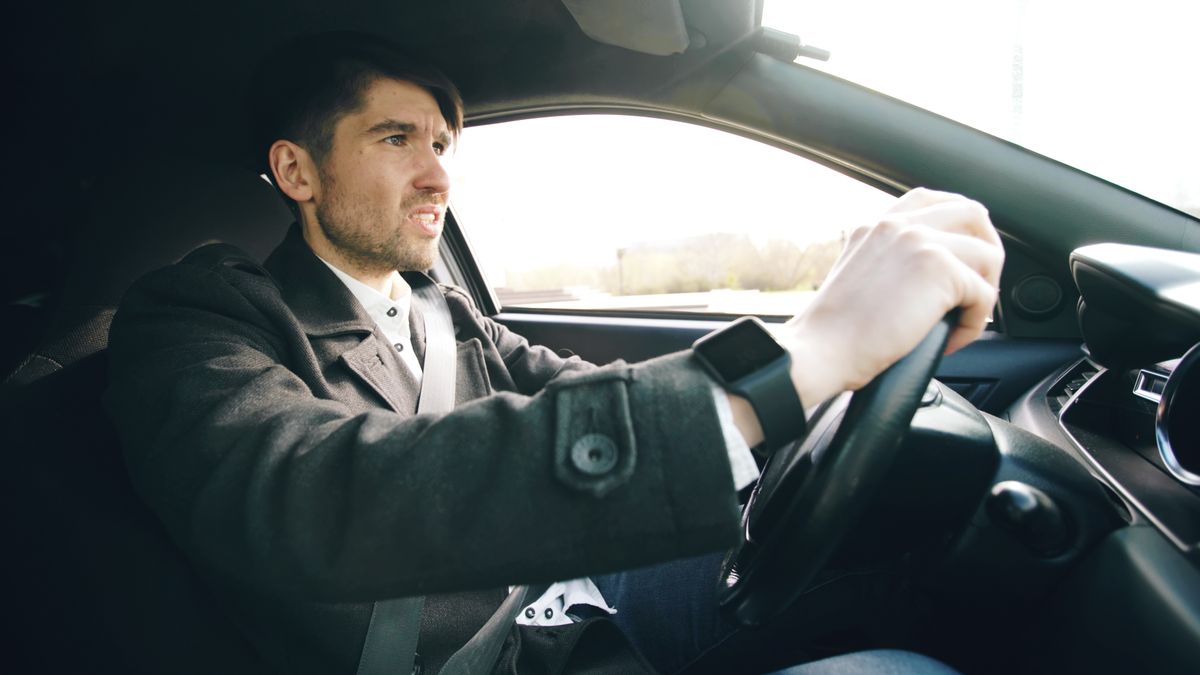 Man driving car, wearing wristwatch, focused on road