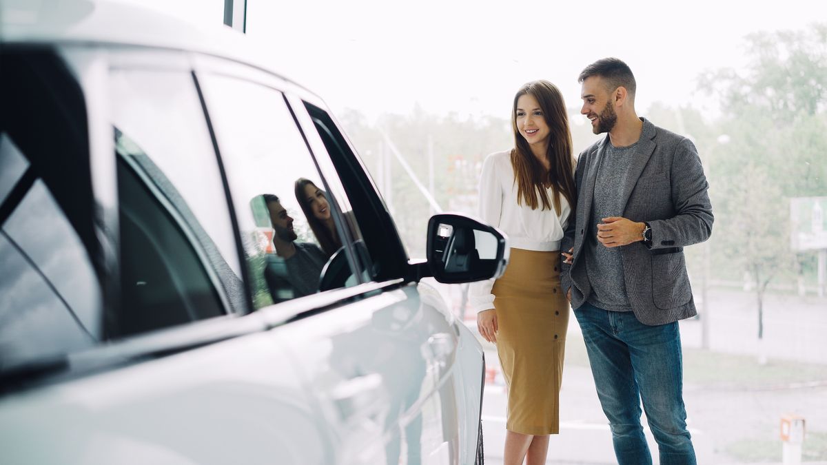 Smiling couple looking over a new car at a dealership