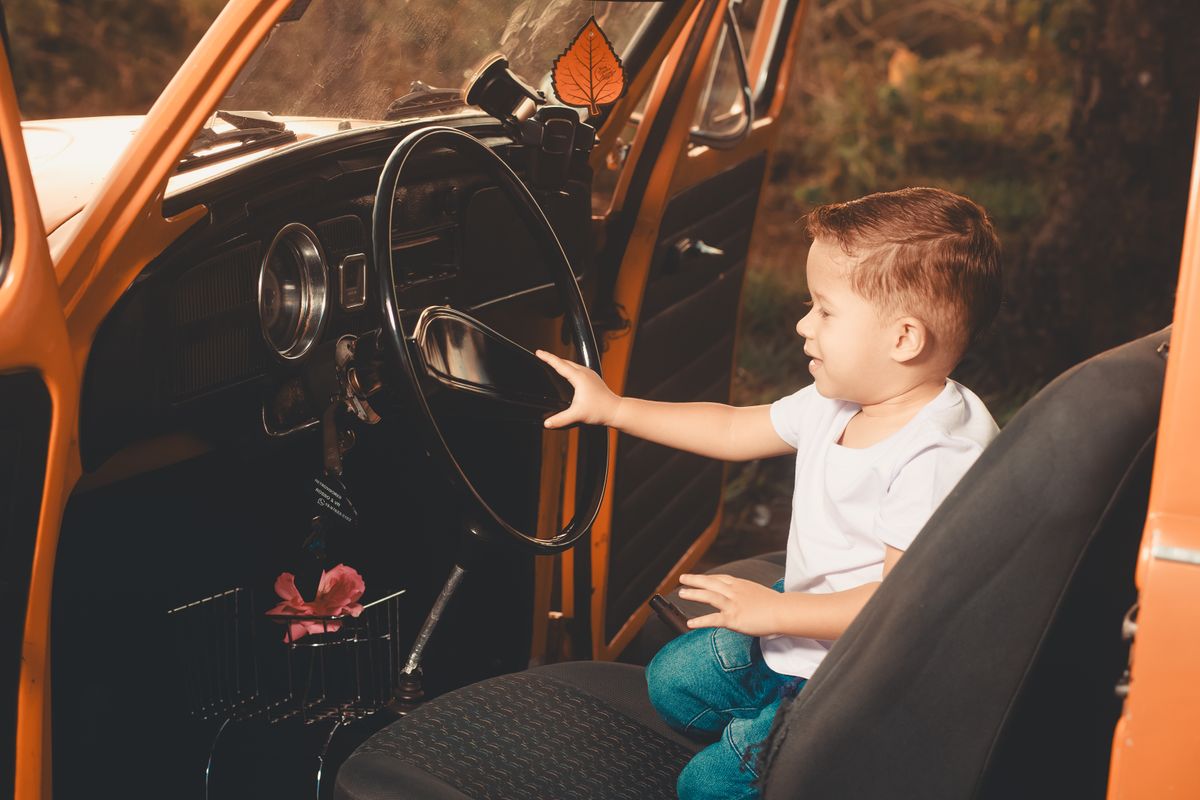 A young boy sits in a classic car