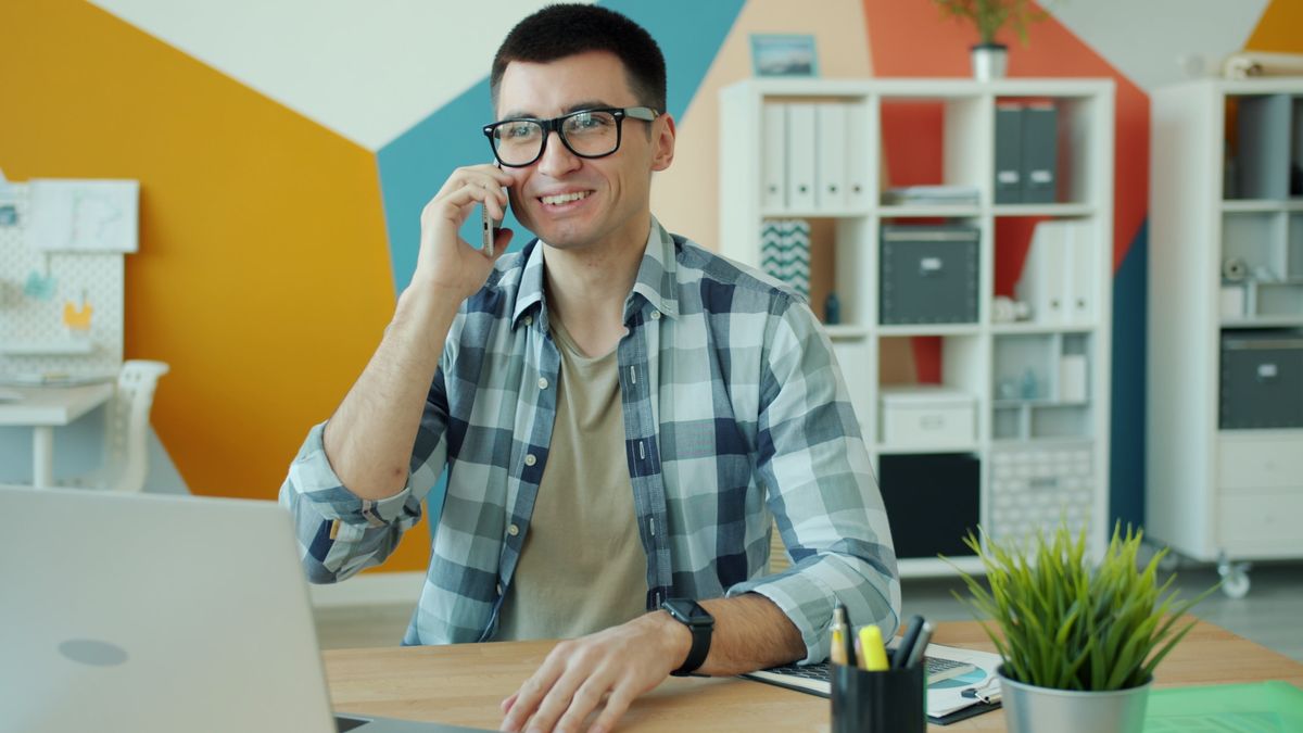 Smiling businessman talking on phone at desk in modern office