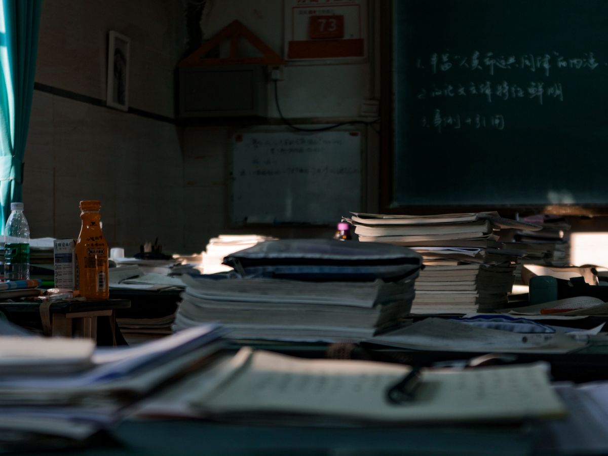 Messy tables with big heaps of papers and stationery in dark room