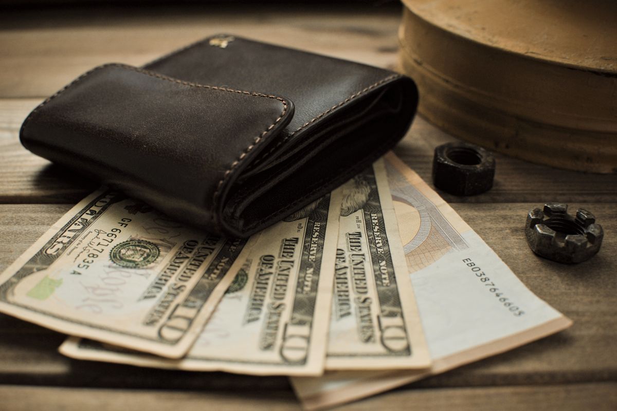 Close-up view of a leather wallet with US dollar bills on a wooden table