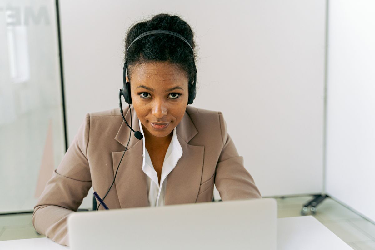Confident woman in call center setting wearing headset and suit