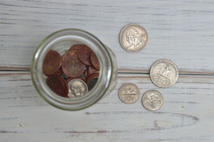 Top view of a jar filled with coins placed on a wooden table