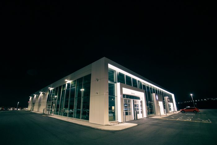 Low angle of car salon with glowing illumination and car on parking lot at night