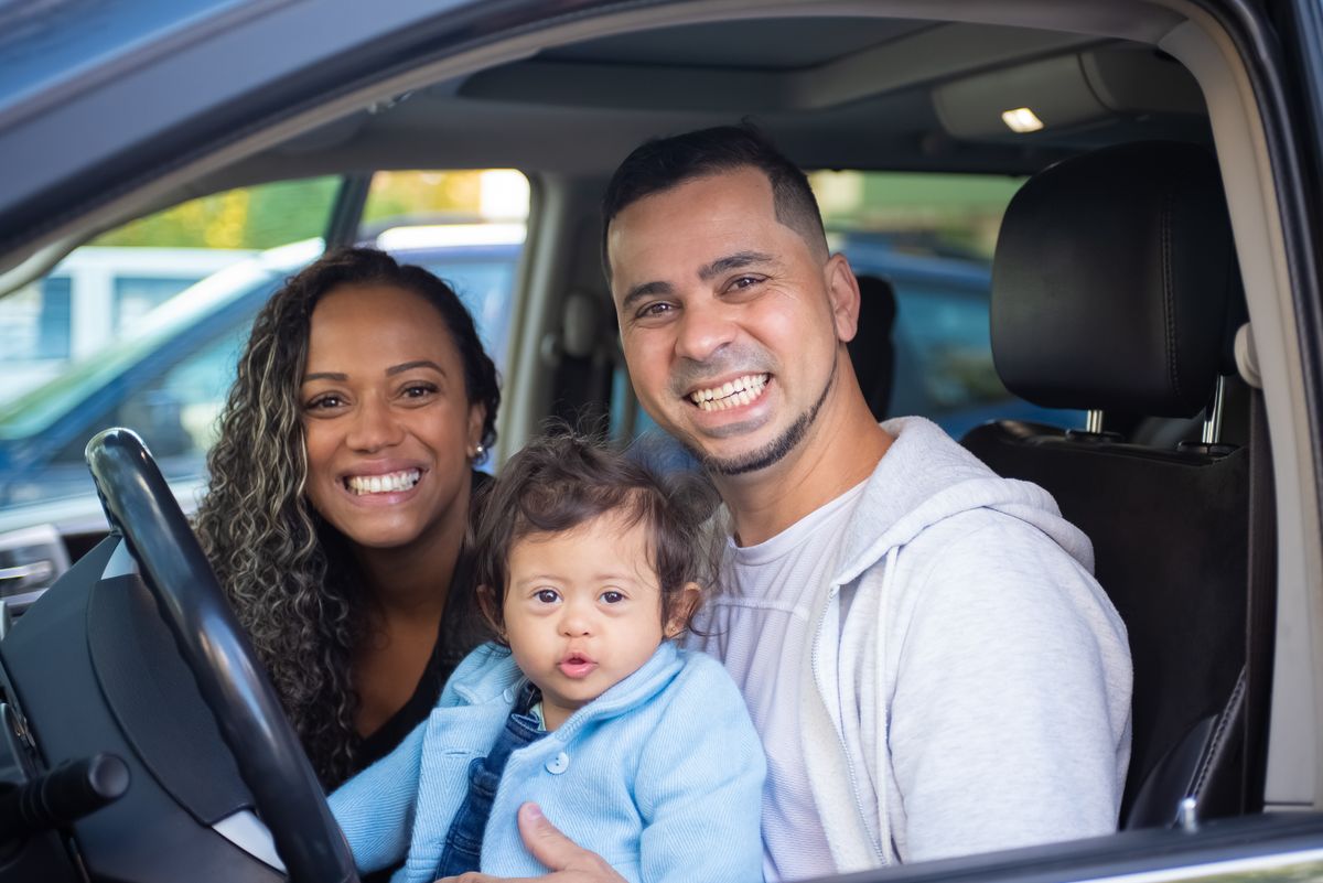 Family of three smiling in a car