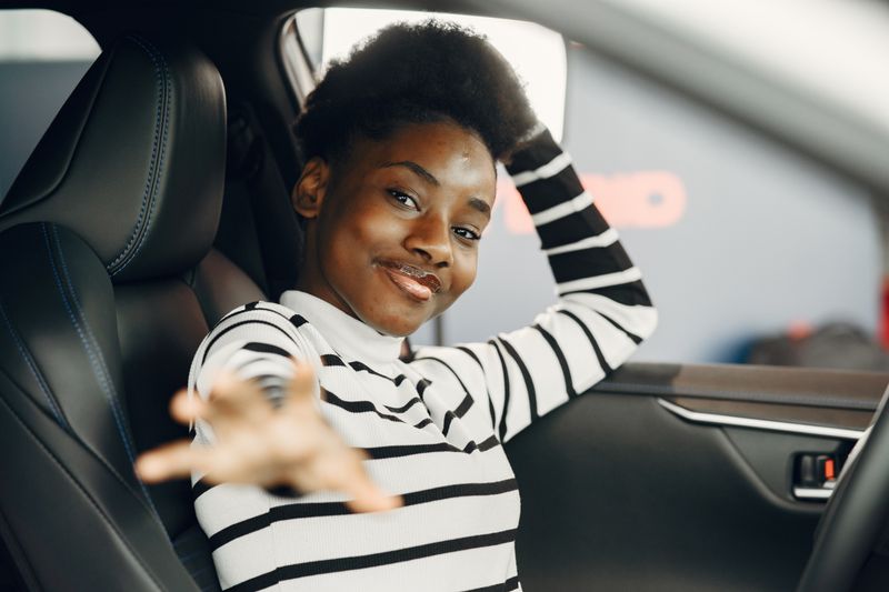 A young woman smiling in the driver's seat of her car