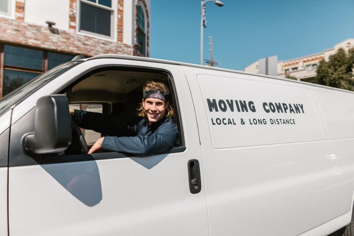 Portrait of a smiling moving company driver in a van on a sunny day outdoors