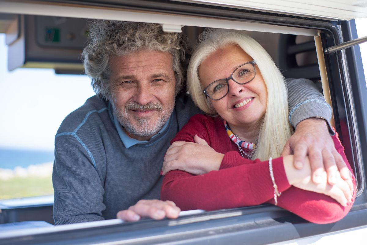 Elderly couple sitting inside the car smiling