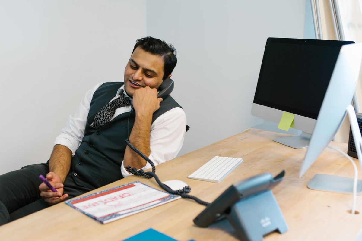 Smiling businessman engaged in a phone conversation at a modern office desk