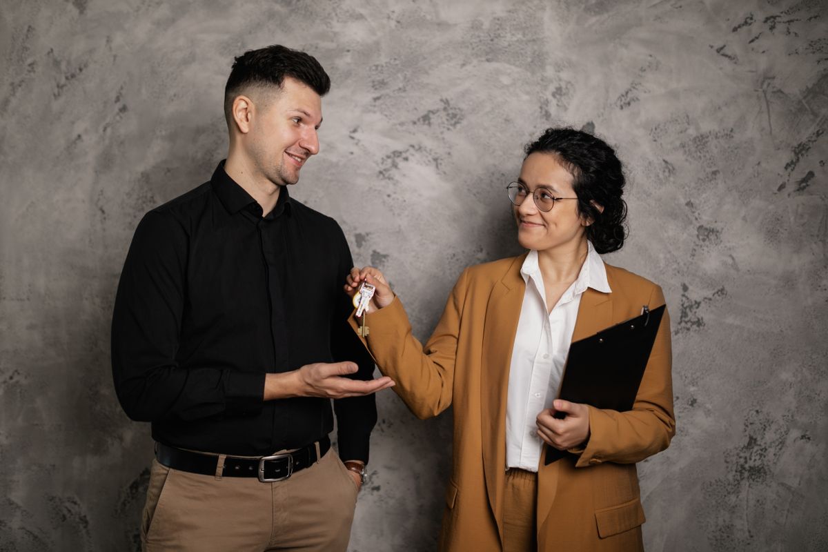 A real estate agent smiling as they hand over house keys to a new homeowner