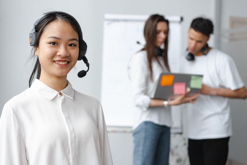 Friendly female call center agent with headset smiling in office setting