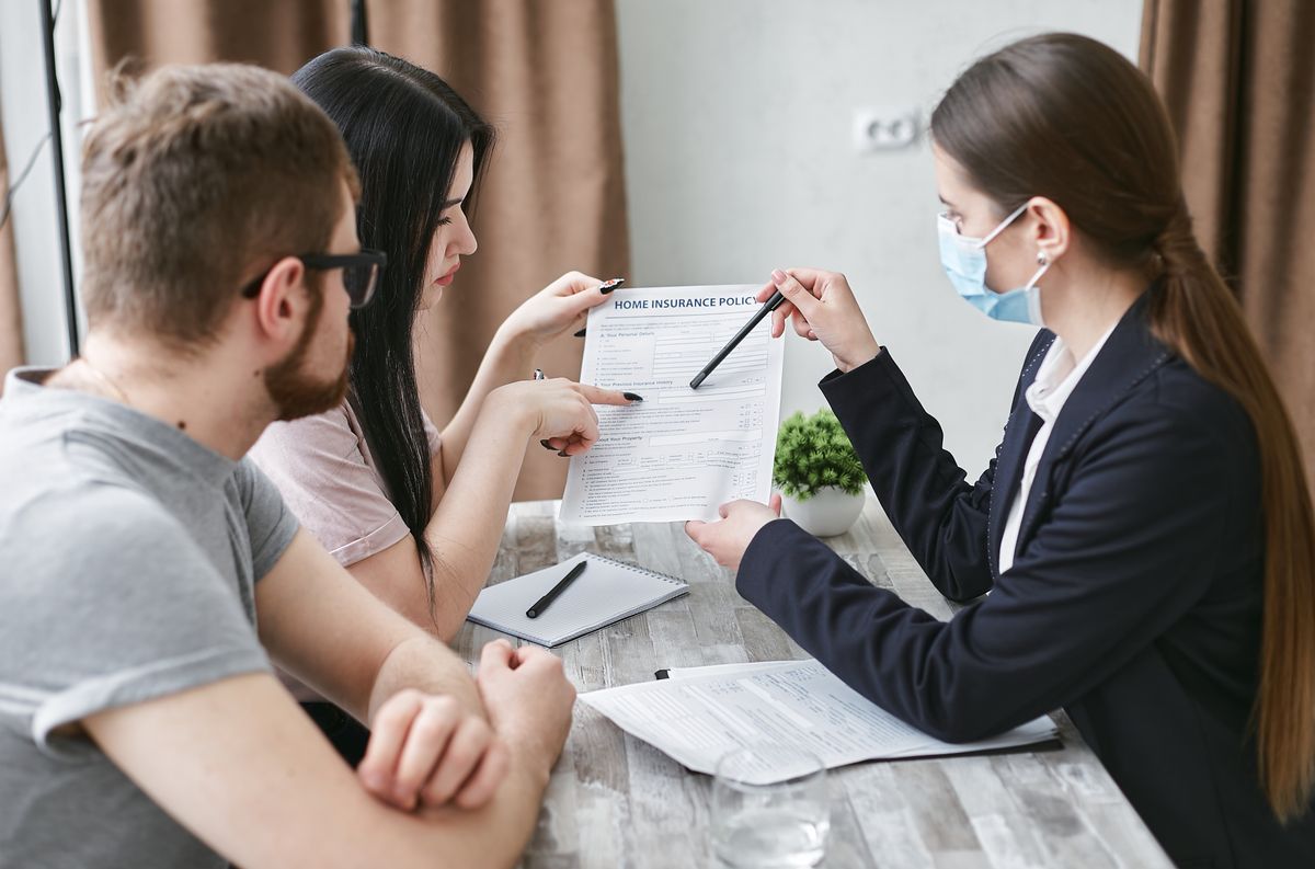 Three adults discussing an insurance policy at a meeting table