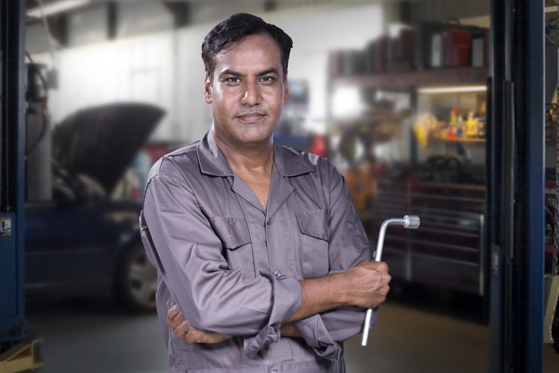 A mechanic holding a lug wrench in an auto repair shop
