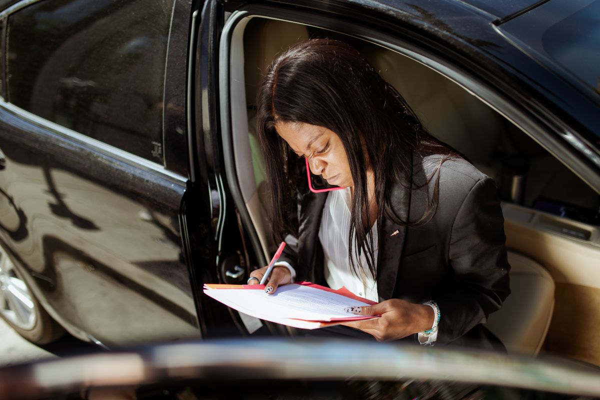 A focused businesswoman analyzes documents while sitting in her car