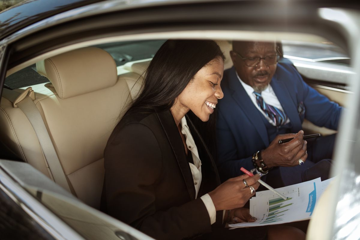 Two business professionals in a car discussing strategies and analyzing charts