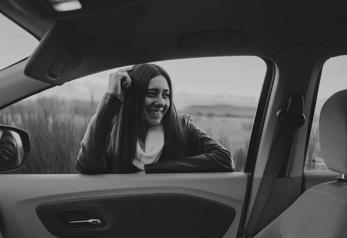 A smiling woman leans on the car window