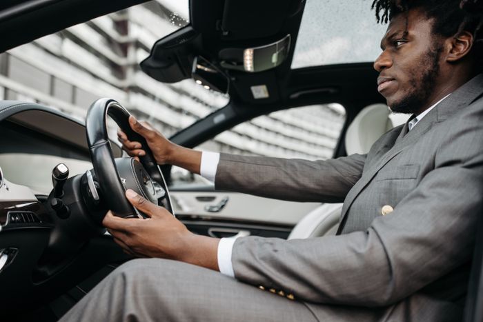 Man in gray suit driving a luxury car, focused on the road