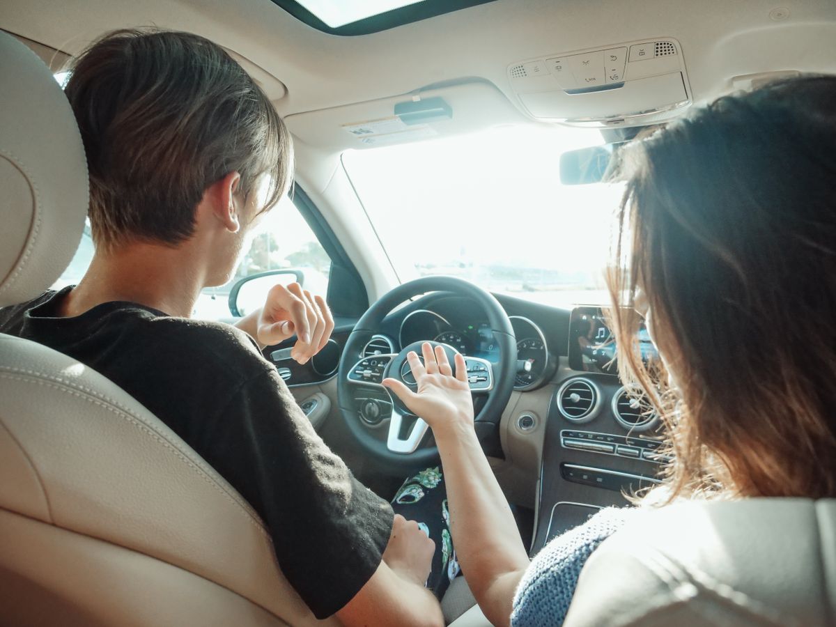 Two adults talking inside a car during the day
