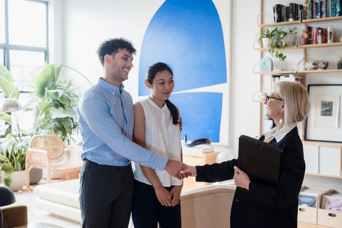 Smiling couple meeting with a real estate agent in a modern living room setting