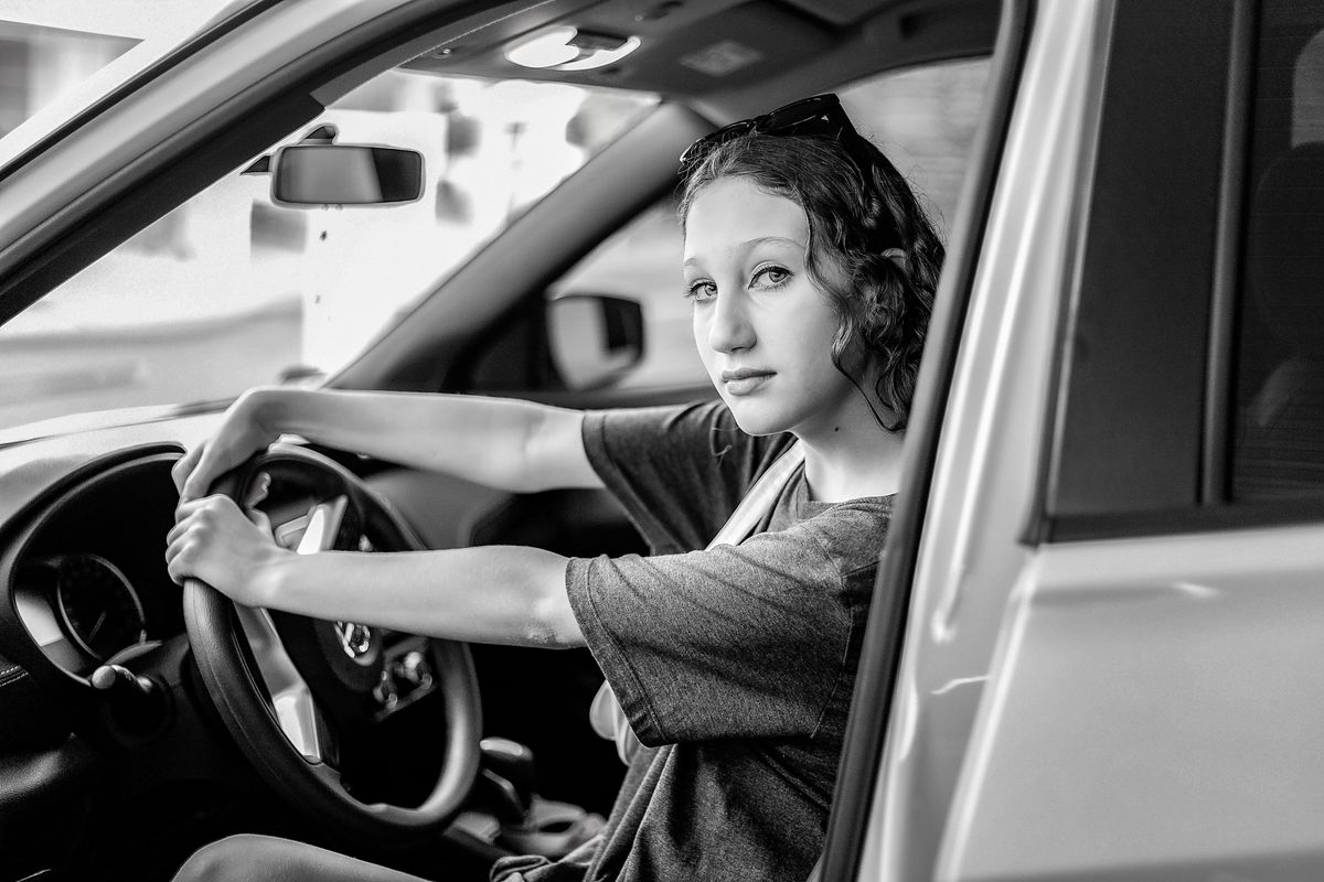 Black and white photo of a young woman confidently driving a car